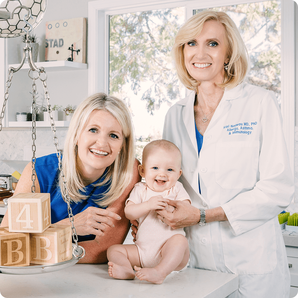 our two women founders with a baby sitting on a counter wearing a pink onesie